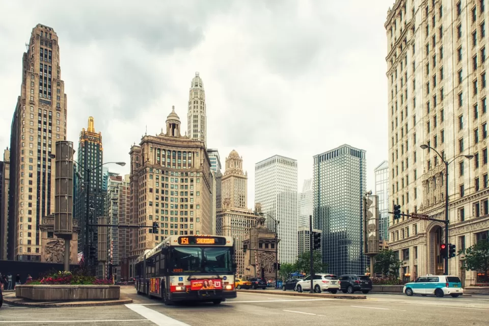 Public transit bus on Chicago street with tall historic buildings in background.